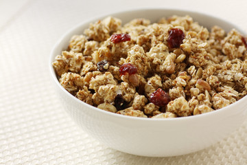 Granola with dried cranberry, raisin, and almond in white bowl