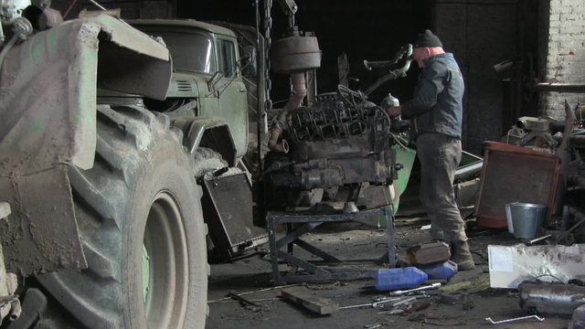 An auto mechanic works with old car