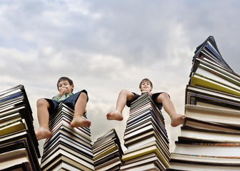 Little boy sitting on large stack of books