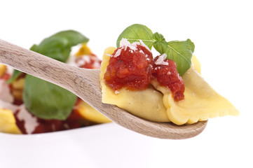 Raviolis with tomato sauce on a wooden spoon