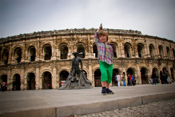 Fototapeta na wymiar Enfant jouant devant les arènes de Nîmes