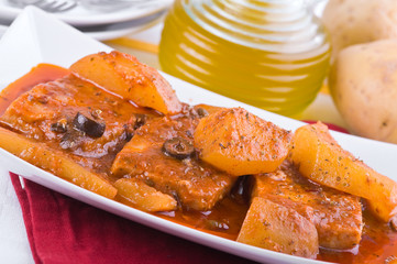 Fish with potatoes and black olives.