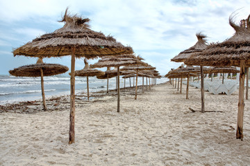 Stormy seacoast with parasols on the sandy beach