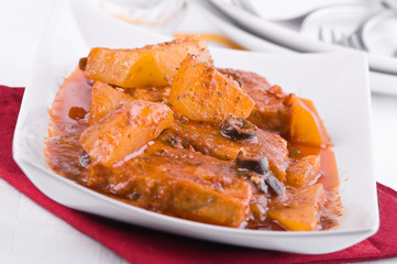 Fish with potatoes and black olives.