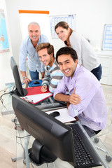 Four people gathered round a computer in a classroom