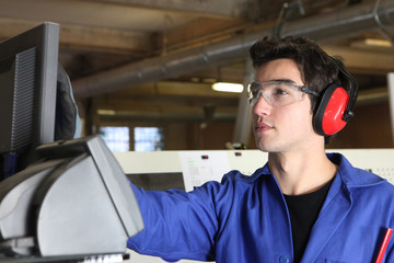 Young man operating machine in factory