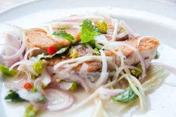 Spicy salad with fried fish and green herb in Thai style