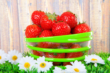 Bowl with fresh strawberries on grass