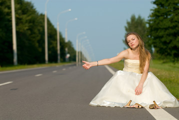 Fototapeta na wymiar The bride in her wedding dress waiting car on road