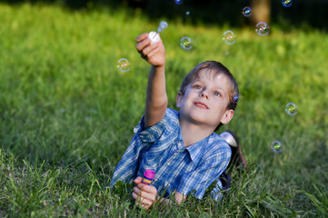 Счастливый мальчик  пускает мыльные пузыри