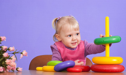 A small charming Caucasian baby plays with toy