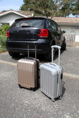 Closeup of suitcases set by a car in driveway