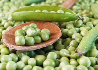 Fresh raw green pea  seeds on wooden spoon