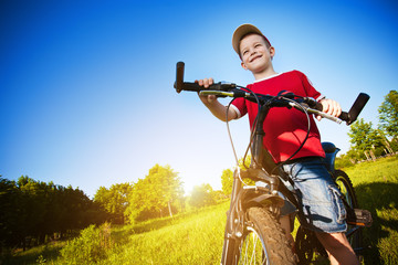 boy with bike standing against the blue sky