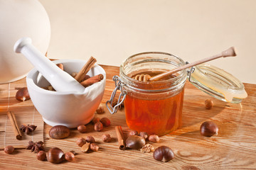 Honey jar next to a mortar filled with cinnamon sticks