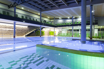 filled indoor swimming pool with colored tiles and illumination