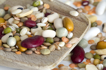 Mixed vegetables on wooden spoon and a white background