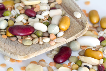Mixed vegetables on wooden spoon and a white background
