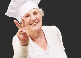 portrait of cook senior woman doing approval gesture over black