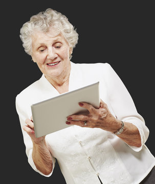 Portrait Of Senior Woman Touching Digital Tablet Over Black Back