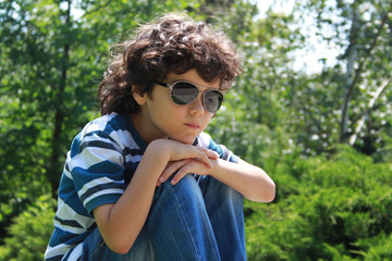 Portrait of a curly boy sitting with head propped on his knees