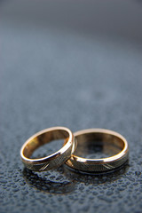 Wedding rings with rain drops on dark grey background