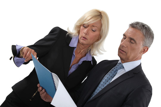 Businessman And Businesswoman Reading A Report