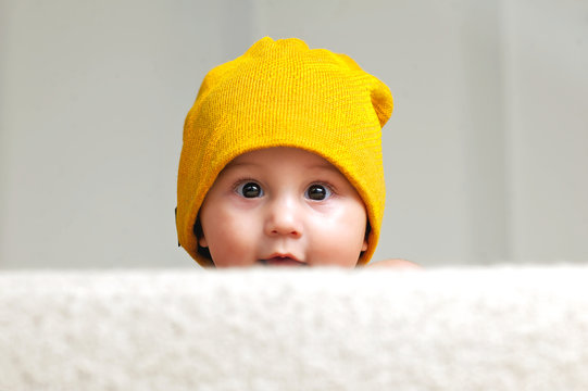 Cute Baby with a Beanie Hat behind a Sofa