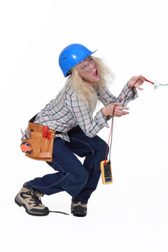 Electrocuted tradeswoman holding a multitester