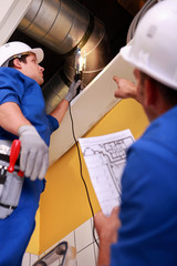 Two workers inspecting ventilation system - obrazy, fototapety, plakaty