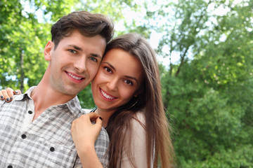 Smiling young man and woman stand in park;