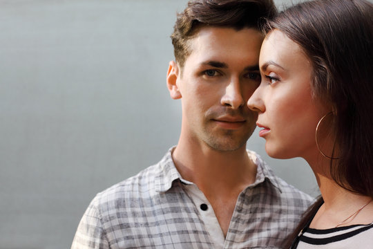 Beautiful Pensive Man And Woman Stand Near Gray Wall;