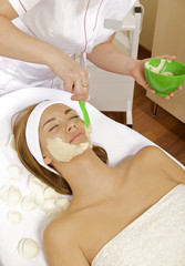 young woman getting beauty skin mask treatment on her face with