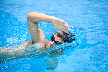 Young man swimming the front crawl in a pool