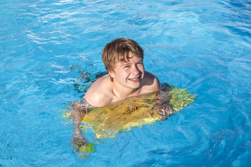 boy relaxing on a surfboard in the pool
