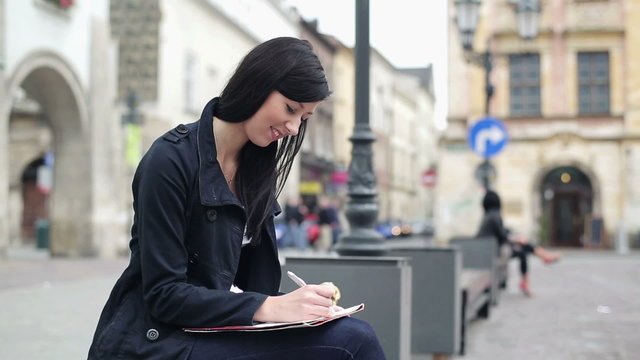 Young student writing notes in the city