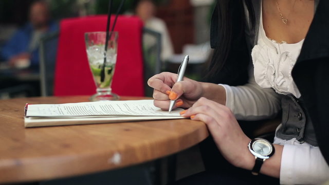 Female student hands writing notes in cafe