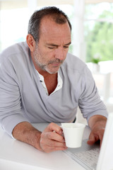 Senior man connected on internet with laptop at home