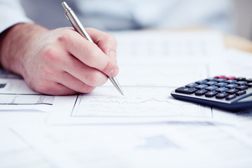 Financial data analyzing. Counting on calculator.
