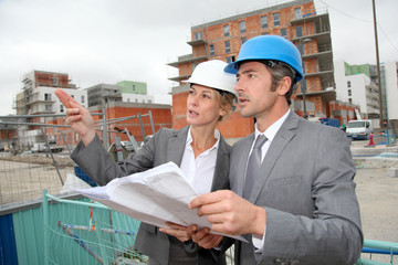 Construction engineers checking plan on building site