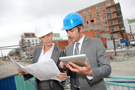 Construction engineers checking plan on building site