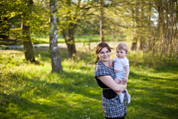 Fototapeta premium Young mother and toddler boy playing in the summer garden