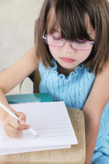Child Sitting at School Desk With Glasses