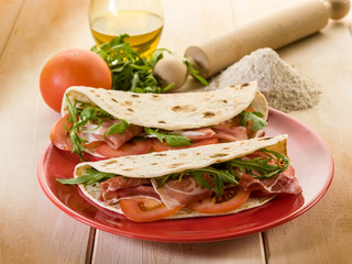 piadina with ham arugula and tomatoes, typical italian sandwich