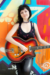 Closeup portrait of a happy young girl with retro guitar and gra