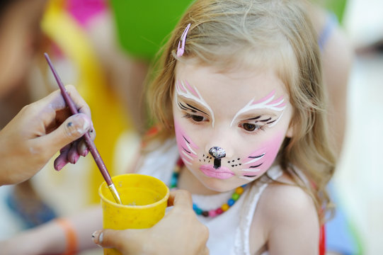 Adorable girl getting her face painted