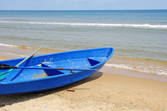 Blue boat on a sandy beach against the sea