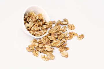 Bowl with walnuts spilled on white