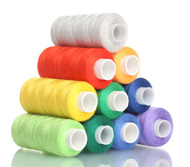 Pyramid of many-coloured bobbins of thread isolated on white