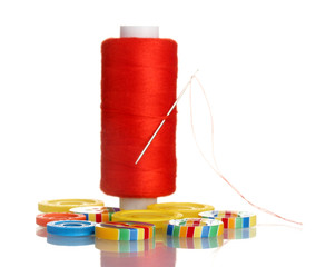 Red bobbin with needle and buttons isolated on white